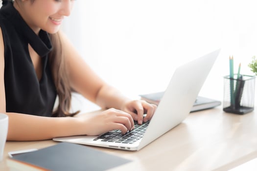 Closeup freelance asian woman working and typing on laptop computer at desk office with professional, girl using notebook checking email or social network, business and lifestyle concept. photo
