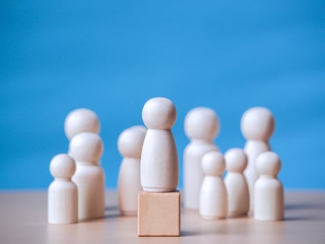 Wooden figure standing on the wooden block to talking leadingship for influence, empowerment and inspiration for crowd. Leader with influence, leader team and successful competition winner concept. photo