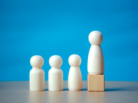 Wooden figure standing on the wooden block to talking leadingship for influence, empowerment and inspiration for crowd. Leader with influence, leader team and successful competition winner concept. photo