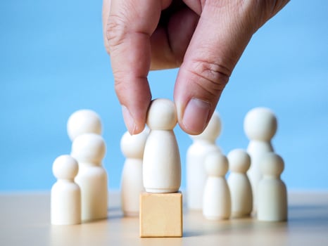 Hand of businessman holding wooden figure standing on wooden block to talking influence, empowerment and inspiration for crowd. Leader with influence, leadership and successful winner concept. photo