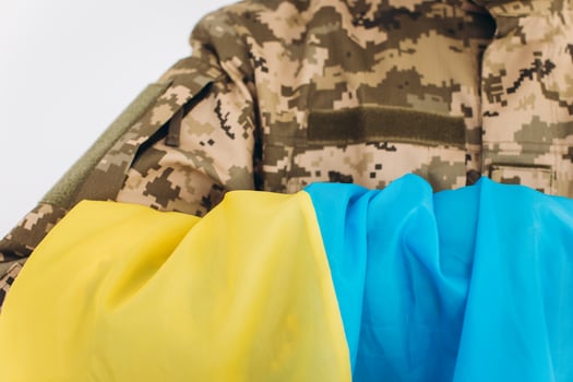 Portrait of an emotional young bearded Ukrainian patriot soldier in military uniform holding a flag in the office photo