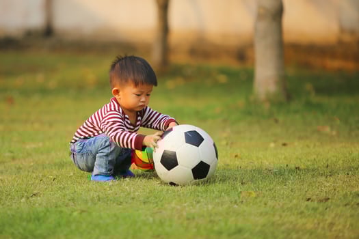Asian boy playing football at the park. Kid with balls in grass field. photo