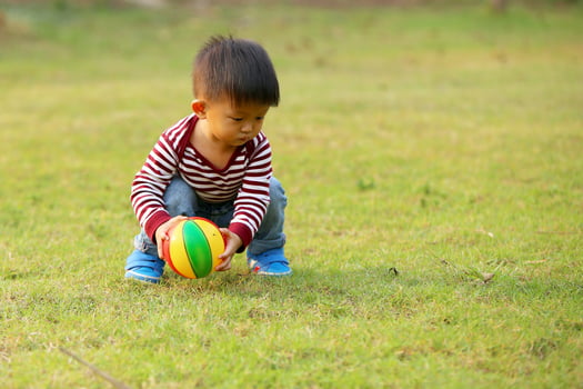 Asian boy playing football at the park. Kid with ball toy in grass field. photo