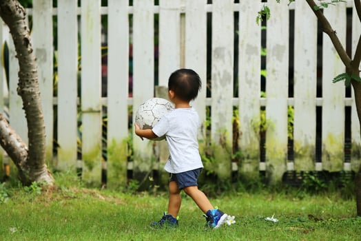 Asian boy playing football at the park. Kid with ball in grass field. photo