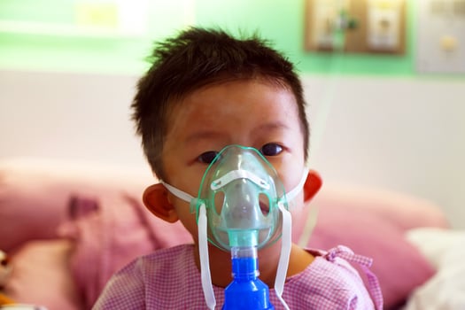 Asian boy making inhalation with a nebulizer in hospital. Sick child. photo