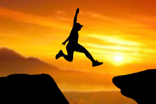 Silhouette of an athlete jumping on a rocky cliff photo