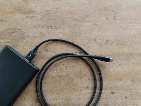 black power bank with USB cable on brown wooden background. photo