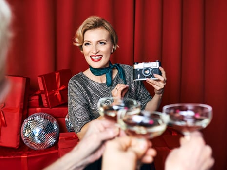 Cheerful beautiful photographer woman at the party celebration on red curtains background. Profession, party concept photo