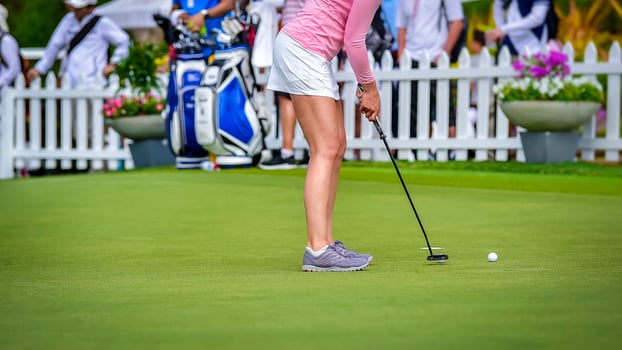 Golfer pushing white golf ball to hole at golf course in golf competition game , sunlight rays and blur background photo