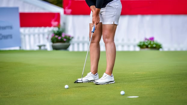 Golfer pushing white golf ball to hole at golf course in golf competition game , sunlight rays and blur background photo