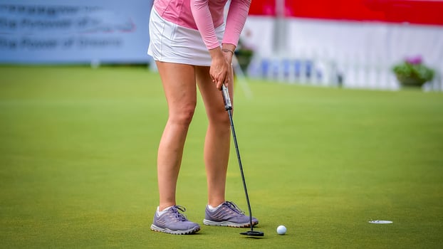 Golfer pushing white golf ball to hole at golf course in golf competition game , sunlight rays and blur background photo