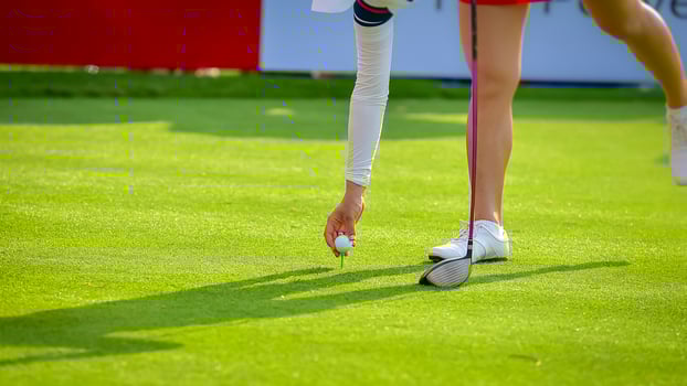 Golfer pushing white golf ball to hole at golf course in golf competition game , sunlight rays and blur background photo