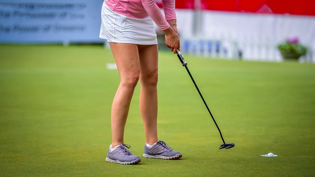 Golfer pushing white golf ball to hole at golf course in golf competition game , sunlight rays and blur background photo