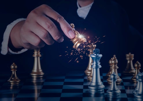 Hand businessman moving the golden knight chess fighting silver knight with fire sparks chess on chess board to successfully in the competition. Management or leadership strategy and teamwork concept. photo