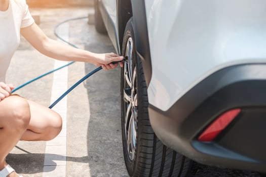 Woman driver hand inflating tires of vehicle, checking air pressure and filling air on car wheel at gas station. self service, maintenance and safety transportation concept photo