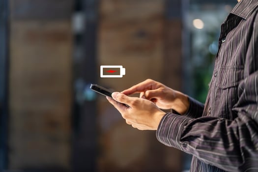 Businessman holding a phone with a low battery charge screen, I need to find a quick charger photo