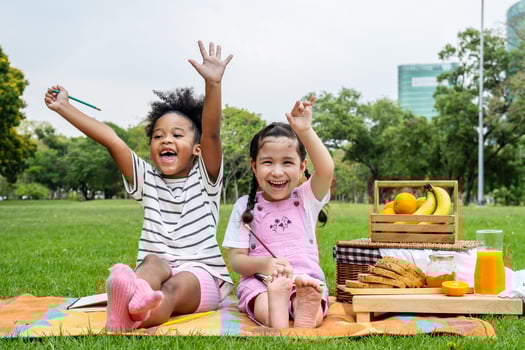 Happy childhood, Two African American little kids girl drawing on notebook with pencil while lying on mat outdoor, Two Little girl having fun raised their hands happily after finishing homework photo
