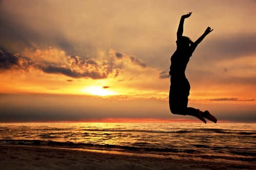 Happy woman jumping on the beach at sunset photo