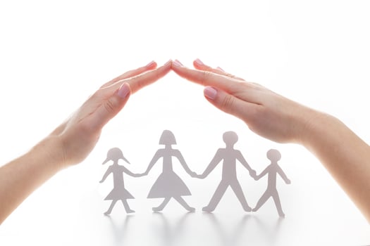 Paper family under hands in gesture of protection. photo