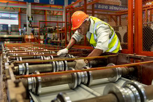 African American industrial worker is checking the setup value of metal sheet roll forming machine inside roof factory for safety industry construction concept photo