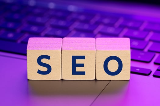 SEO word on wooden blocks on laptop with colorful lights. Search Engine optimization concept photo