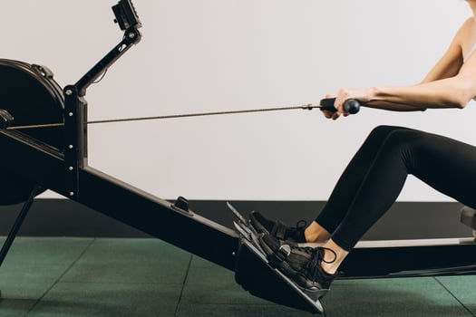 Woman exercising on rowing machine, part of circuit training warmup cardio session photo