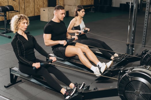 Young man and beautiful women working out with rowing machine at crossfit gym. photo