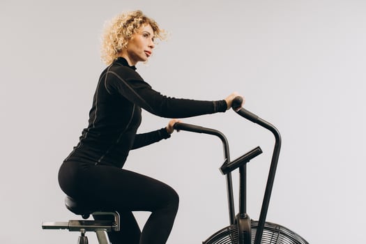 Crossfit woman doing intense cardio training on exercise air bike photo