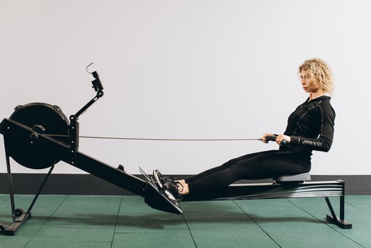 Woman exercising on rowing machine, part of circuit training warmup cardio session photo