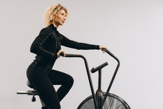Crossfit woman doing intense cardio training on exercise air bike photo