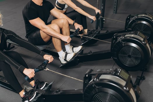 Young man and beautiful women working out with rowing machine at crossfit gym. photo