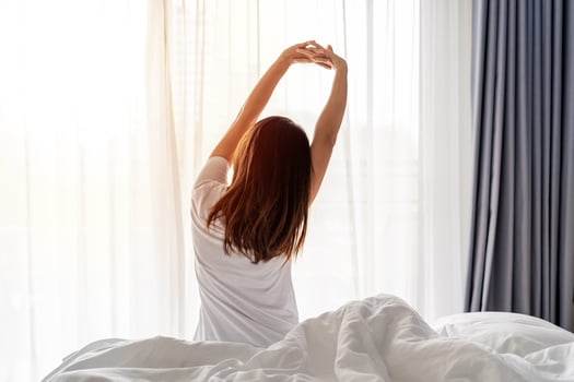 Young asian woman sitting on the bed and stretch oneself in the morning at home photo