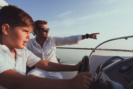 Father and son enjoy their vacation together while riding a luxury boat at sea. Selective focus photo