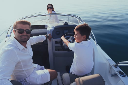 A senior couple in casual outfits with their son enjoy while riding a boat at sea at sunset. The concept of a happy family. Selective focus photo