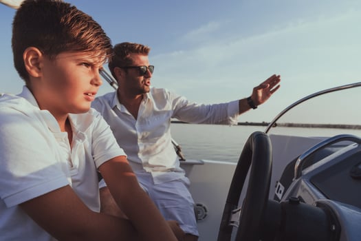 Father and son enjoy their vacation together while riding a luxury boat at sea. Selective focus photo