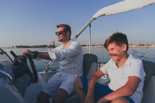 Father and son enjoy their vacation together while riding a luxury boat at sea. Selective focus photo