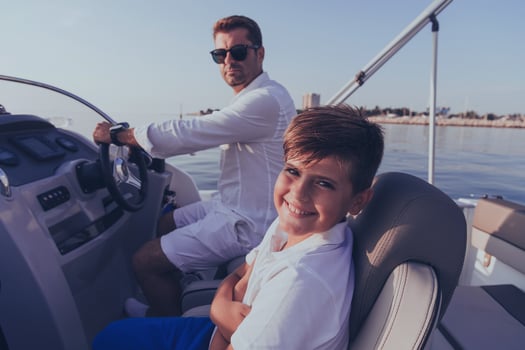 Father and son enjoy their vacation together while riding a luxury boat at sea. Selective focus photo
