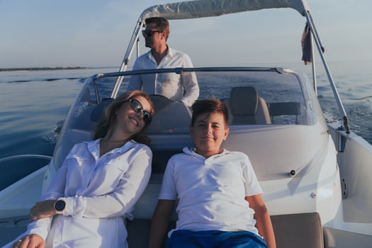 A senior couple in casual outfits with their son enjoy while riding a boat at sea at sunset. The concept of a happy family. Selective focus photo