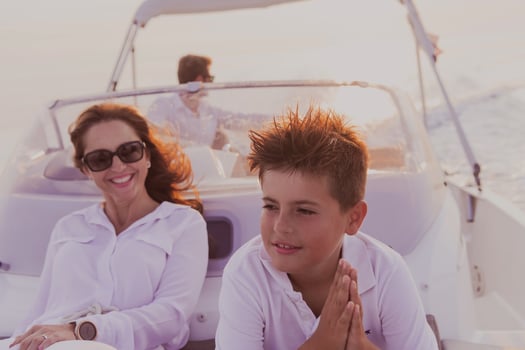 A senior couple in casual outfits with their son enjoy while riding a boat at sea at sunset. The concept of a happy family. Selective focus photo