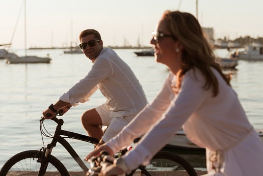 Senior couple enjoying a beautiful morning together riding a bike by the sea. Selective focus photo