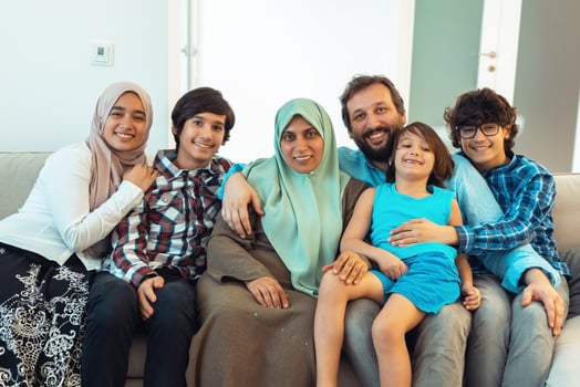 Portrait photo of an arab muslim family sitting on a couch in the living room of a large modern house. Selective focus