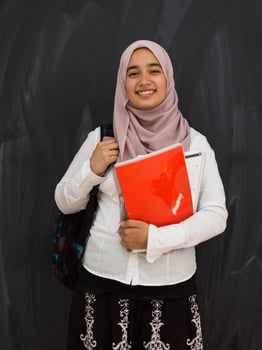 portrait of happy female middle eastern university student against black chalkboard in classroom photo
