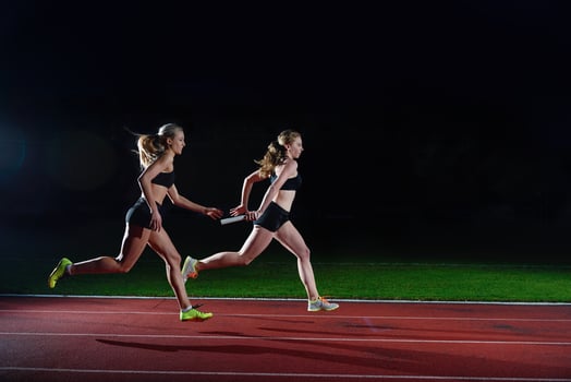 athletic runners passing baton in relay race photo