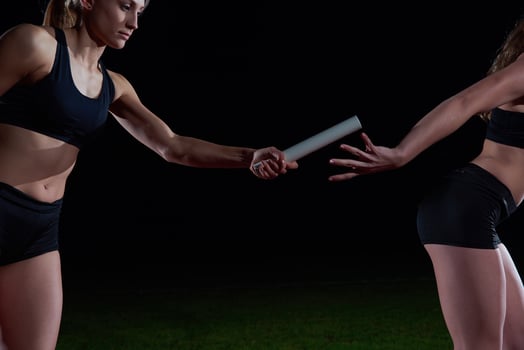 athletic runners passing baton in relay race photo