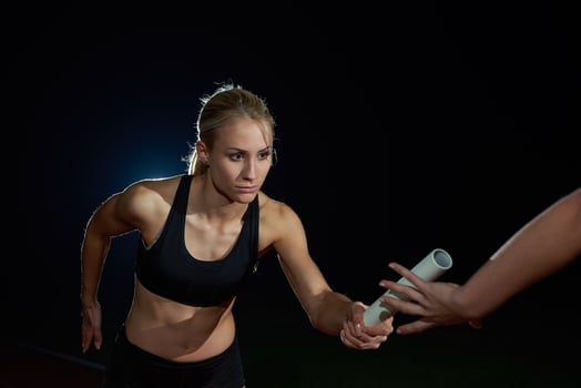 athletic runners passing baton in relay race photo