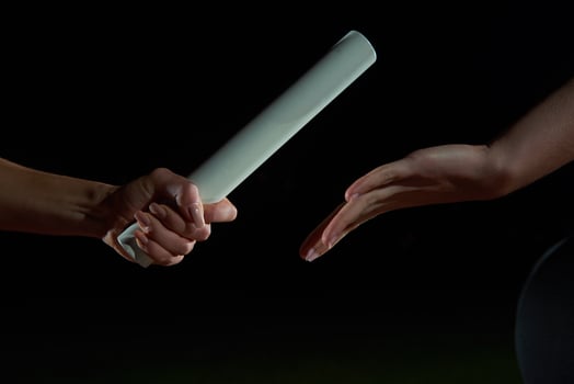 athletic runners passing baton in relay race photo