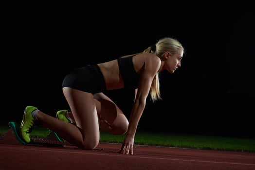 woman  sprinter leaving starting blocks photo