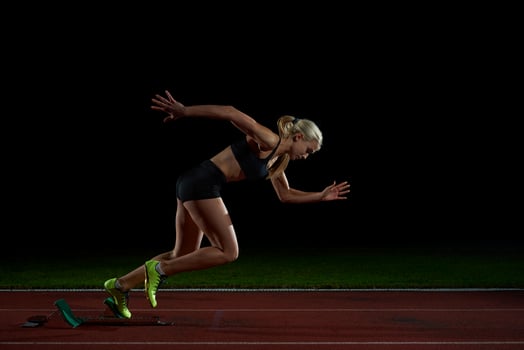 woman  sprinter leaving starting blocks photo