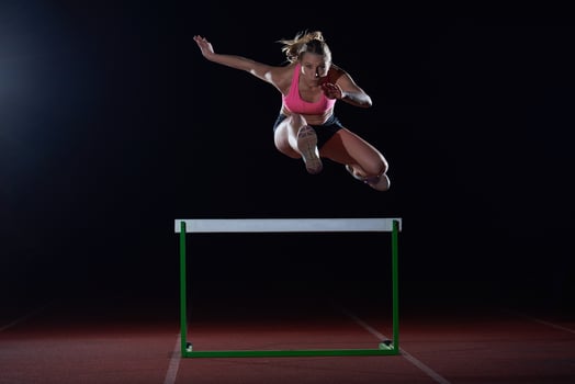 woman athlete jumping over a hurdles photo