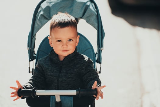 Sweet baby boy in a stroller bicycle outdoors. Little child in a pram. Infant kid in a pushchair. Spring walks with kids. photo
